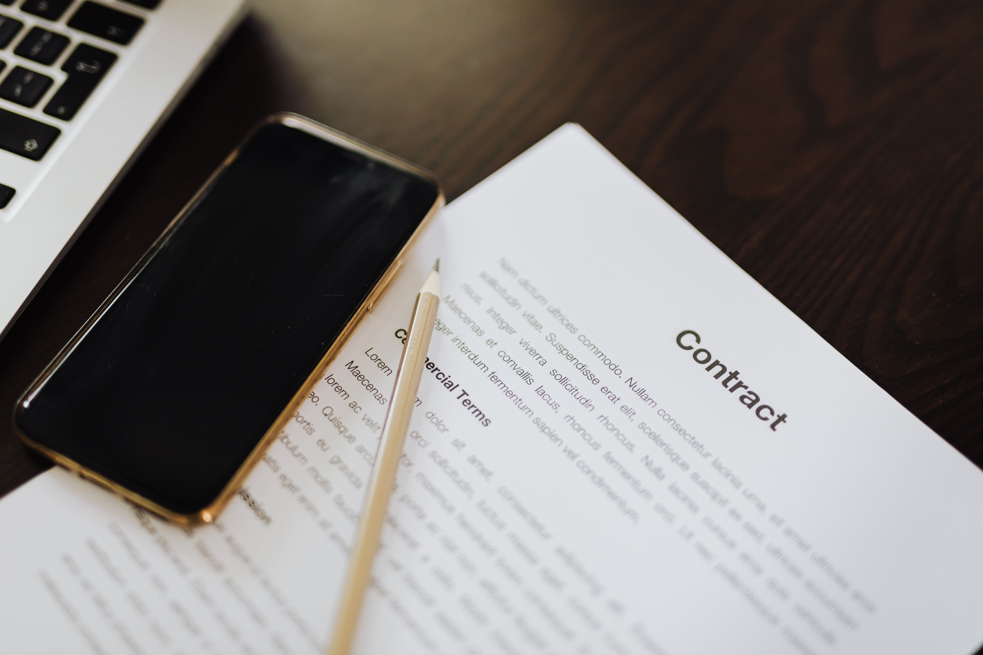 A contract on a desk next to a phone and pencil — the paperwork behind international contractor payments