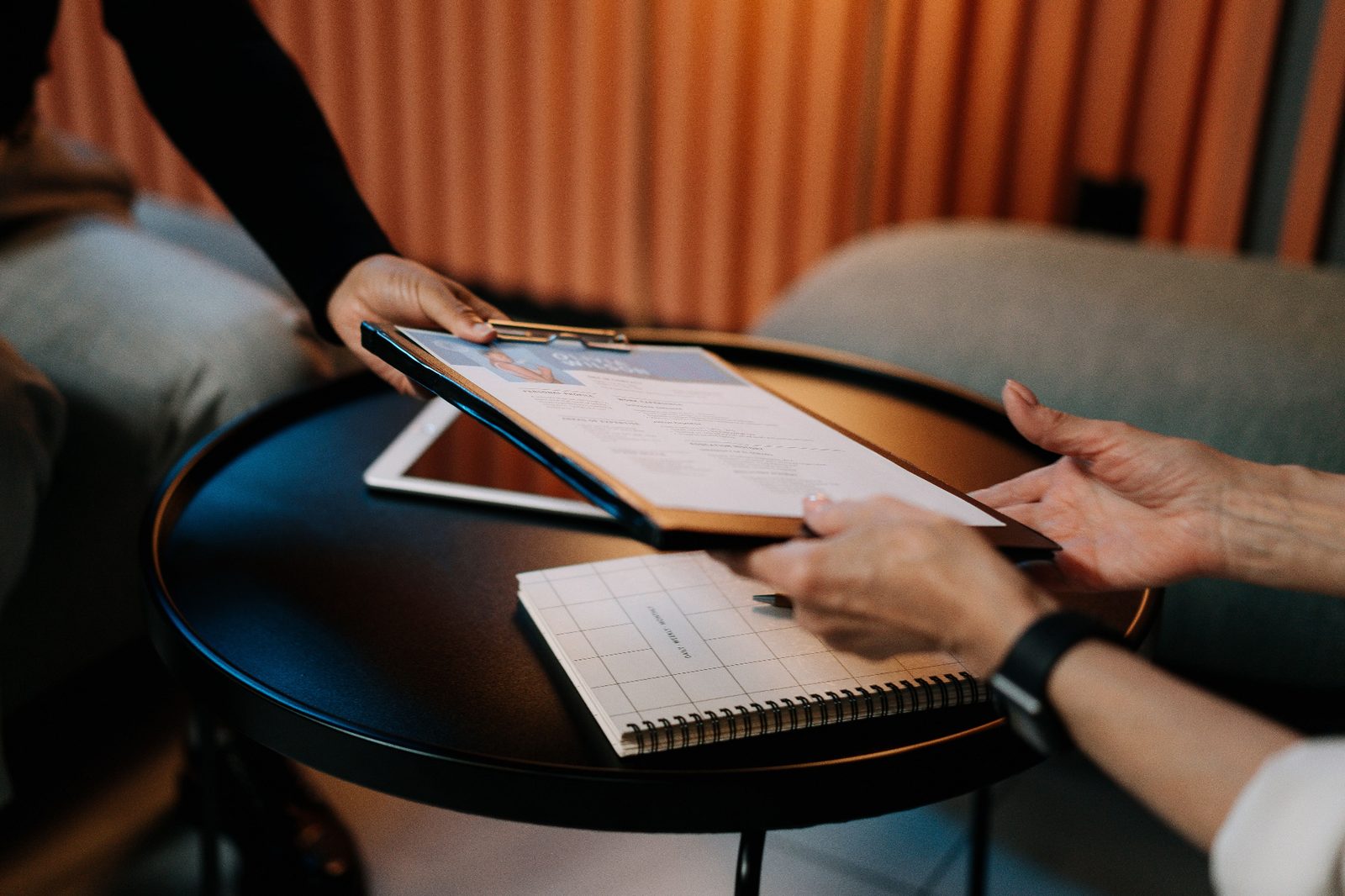 A recruiter hands a shortlist of vetted candidate profiles to a hiring manager